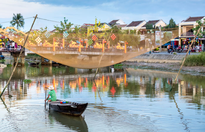  Um homem rema o seu barco de pesca típico em Hoi An, Vietname 