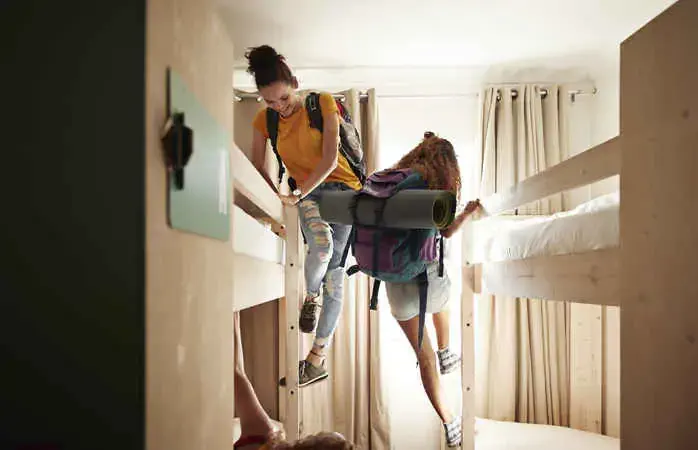 Young women having a good time and hanging out, at youth hostel with bunk beds