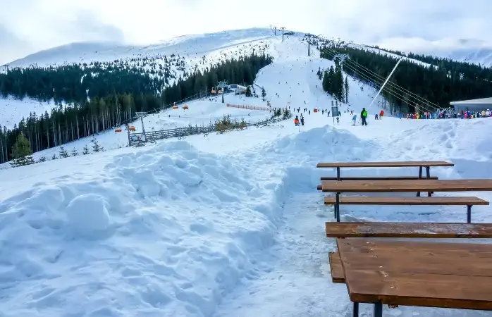 Winter Slovakia. Ski resort Jasna. Overcast. Empty wooden benches and tables near ski slope